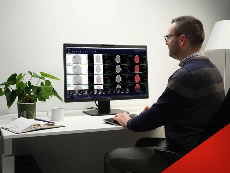 Mann analysiert medizinische Bildgebung auf einem Monitor, während er an einem Schreibtisch mit Pflanzen arbeitet.